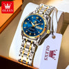 A stainless steel watch with a blue dial and gold accents is displayed in a box with a tag.