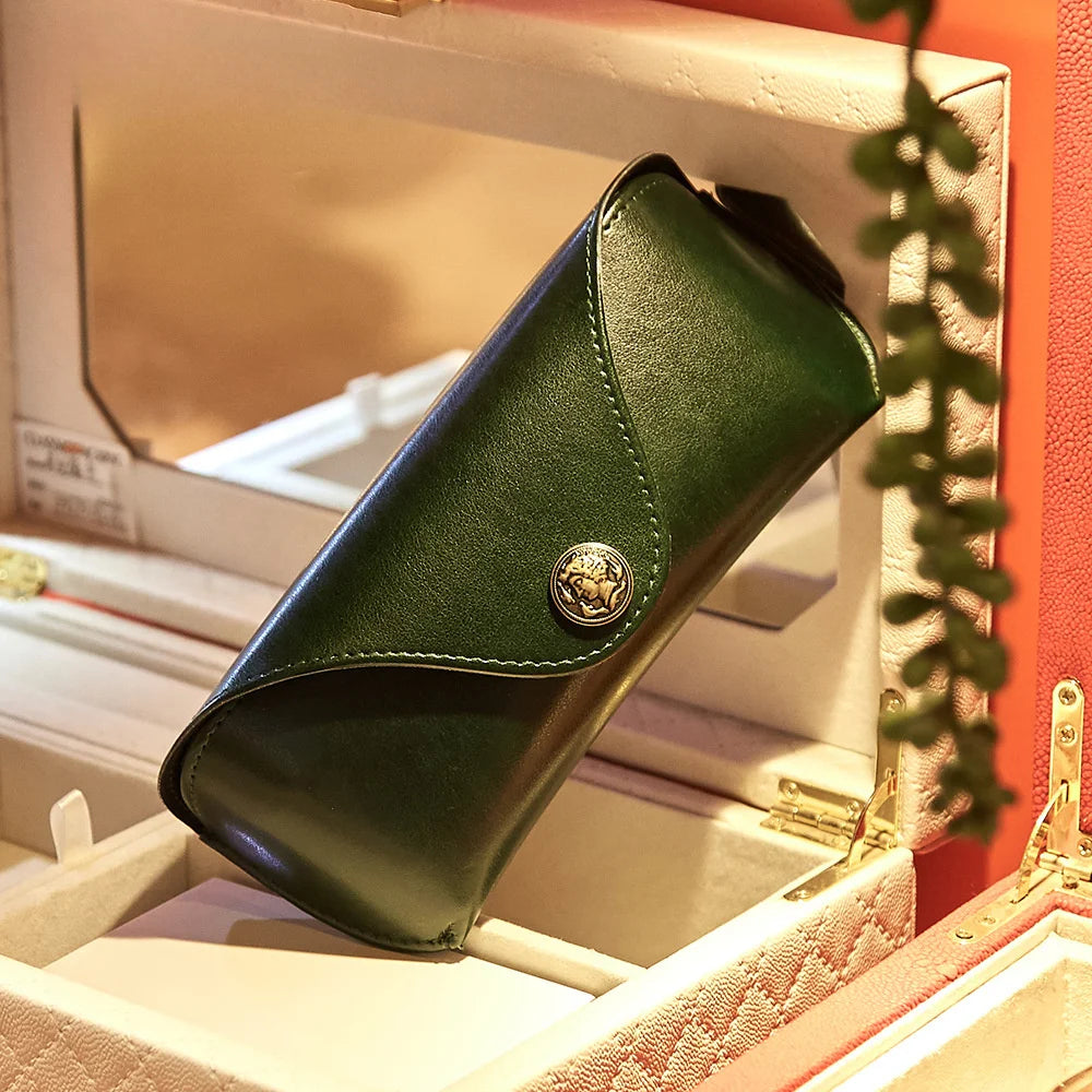 Estuche retro de PU verde oscuro para gafas y joyas, exhibido en una caja de color claro.