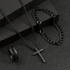 Un ensemble de colliers et bracelets pour hommes en acier inoxydable noir présentés sur une surface sombre.