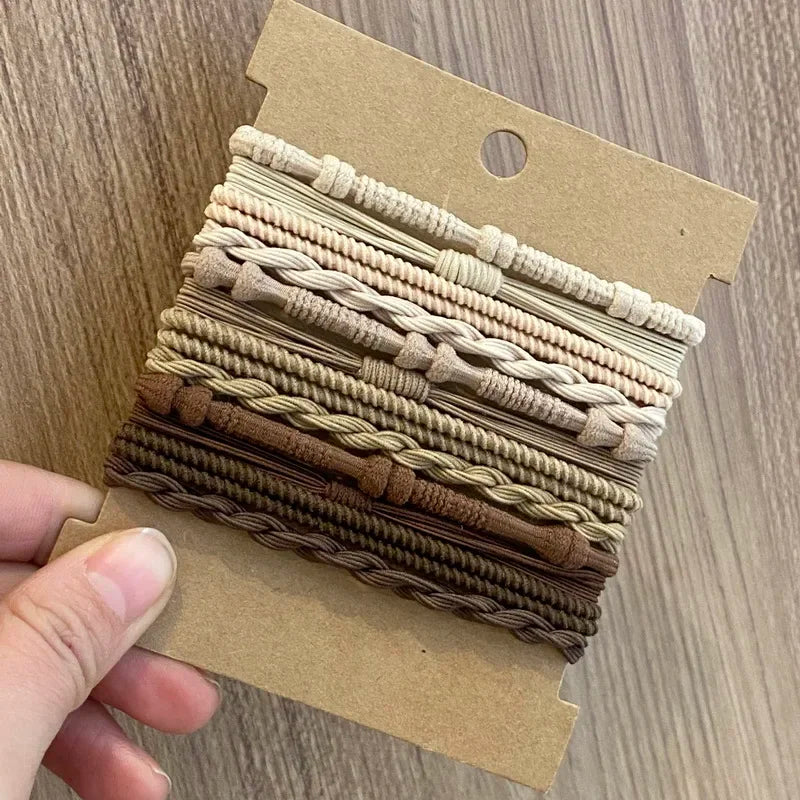 Eine Sammlung beiger und brauner Boho-Elastband-Haargummis in einer Kartonverpackung.