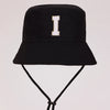 Black sun hat with a large white letter I embroidered on the front and an adjustable cord.