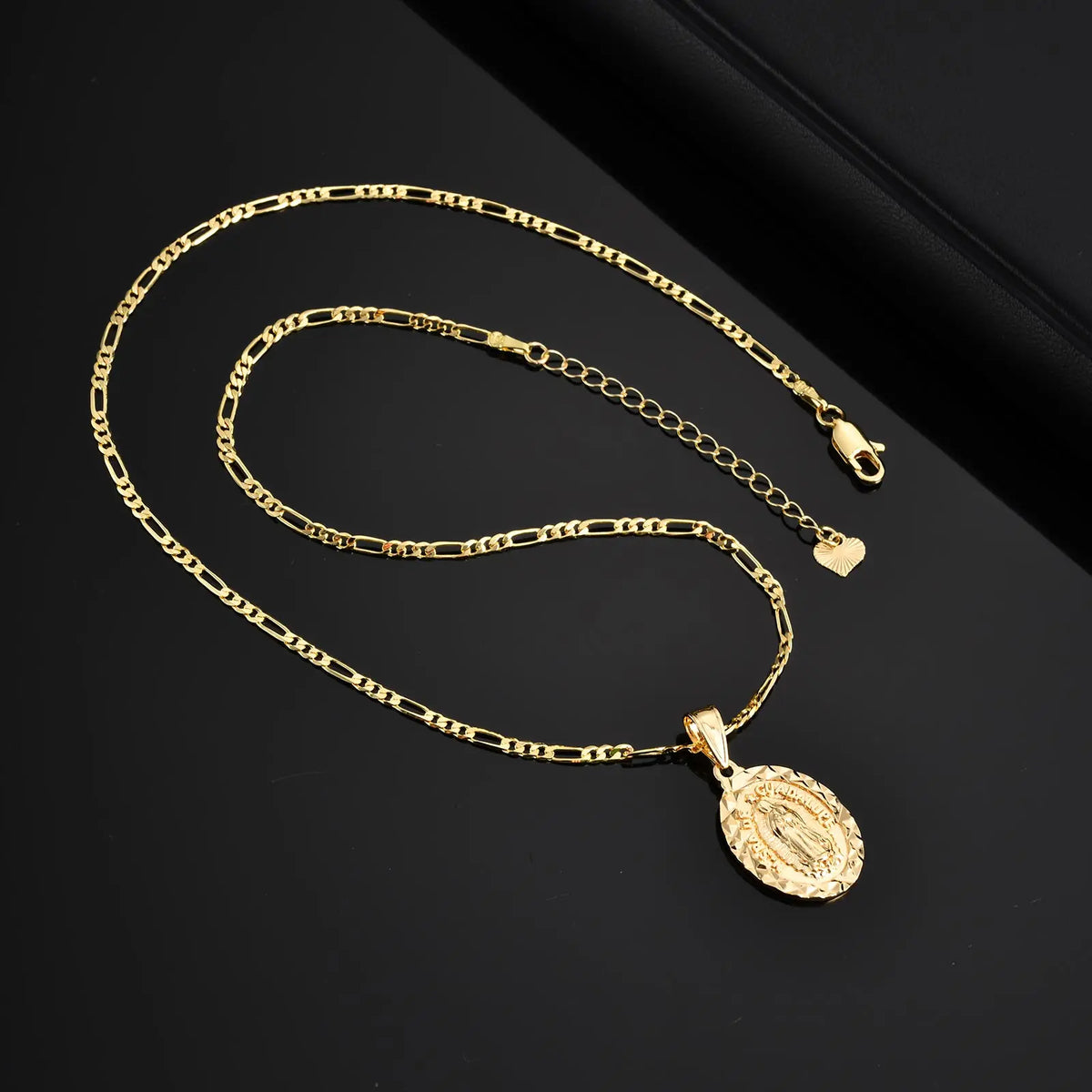 A gold-colored classic Virgin Mary prayer pendant necklace displayed on a dark background.