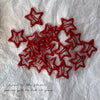 A cluster of red star-shaped snap clips for hair and barrettes set on white fabric.