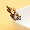 A set of retro cartoon enamel lapel pins featuring a stylized animal character in brown and yellow colors.
