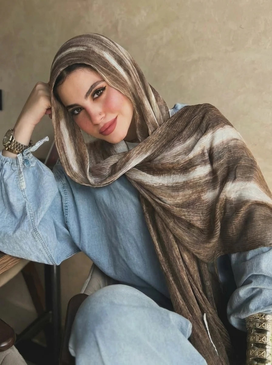 Una mujer vistiendo un elegante pañuelo de hijab de rayas marrón y beige de algodón rayón sobre su cabeza y hombros.