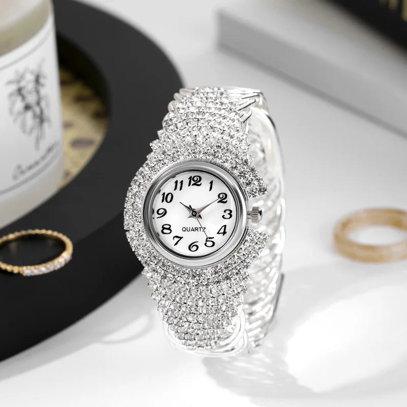 A close-up shot of an elegant silver quartz wristwatch fully encrusted with brilliant rhinestones on a white background.
