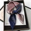 A dark blue silk scarf tied in a bow displayed in a wooden frame.
