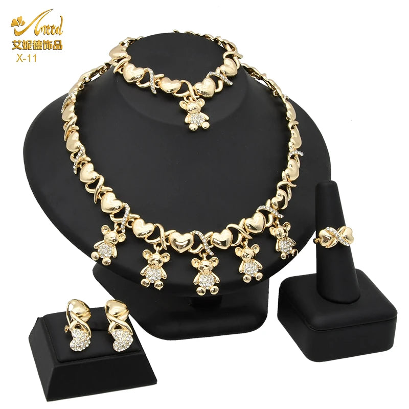 A set of 18K gold heart crystal jewelry including a necklace and earrings displayed on a black stand.