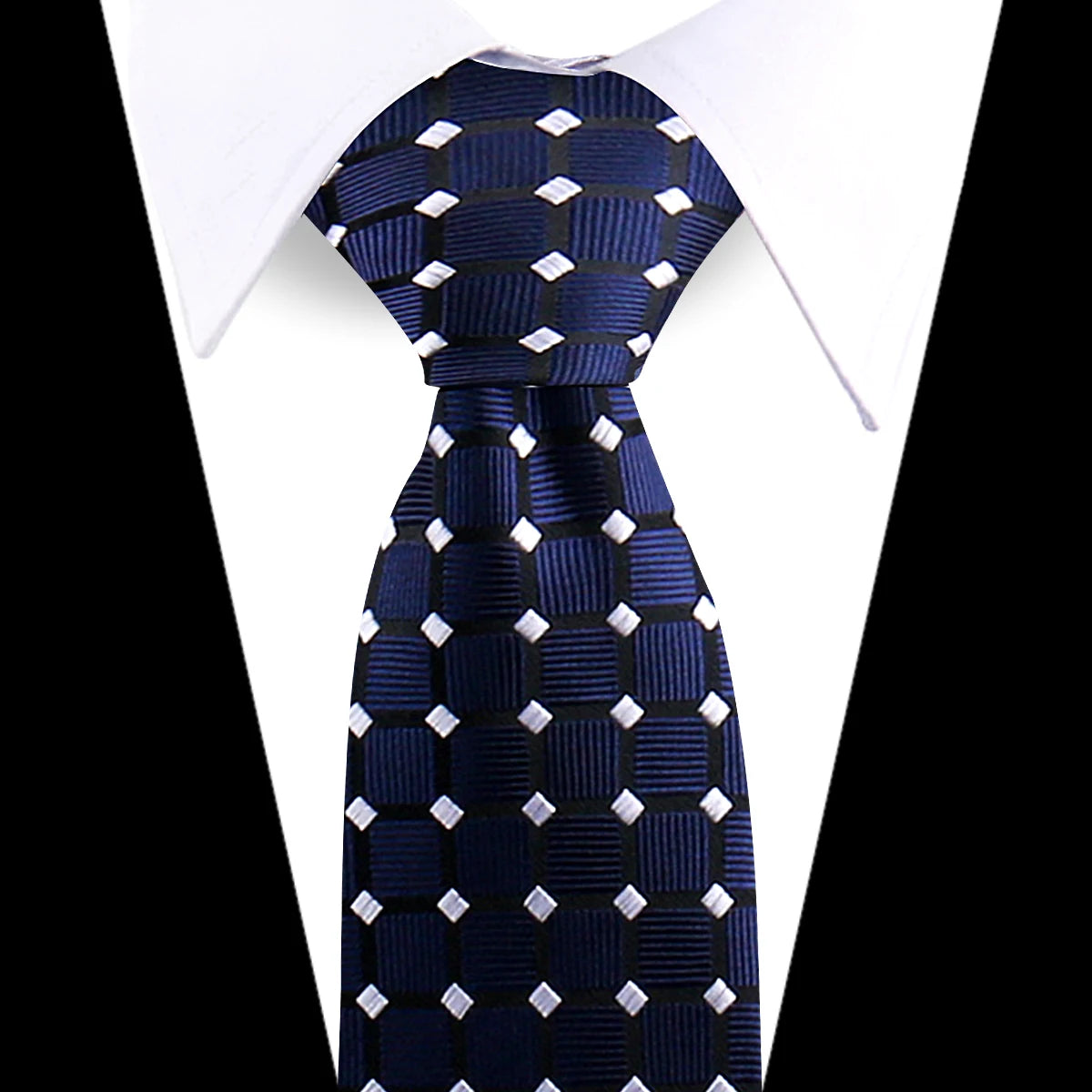 Navy blue silk necktie with white geometric pattern worn under a white dress shirt.