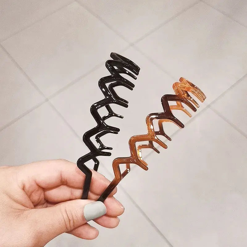 A hand holds a set of black and brown anti-slip toothed hair accessories.