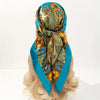 A turquoise satin silk scarf tied around a blonde wig, featuring an ornate gold and teal paisley pattern.