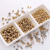 A collection of gold and silver spacer beads scattered on a white surface.