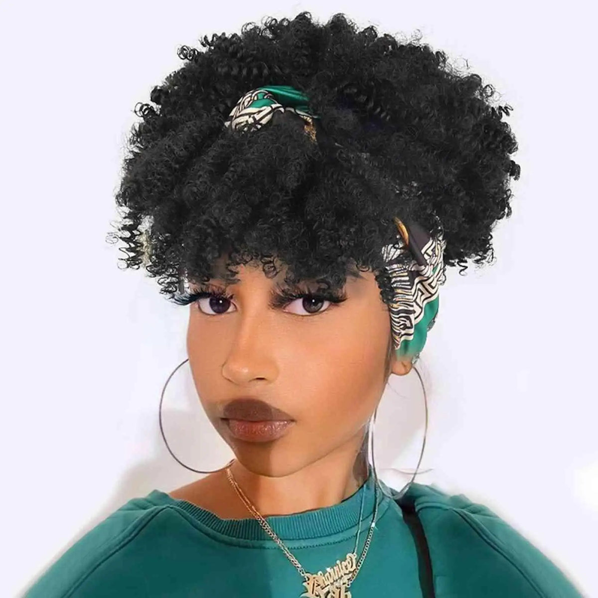 Una mujer vistiendo una peluca afro rizada negra con una diadema estampada y un collar de oro.