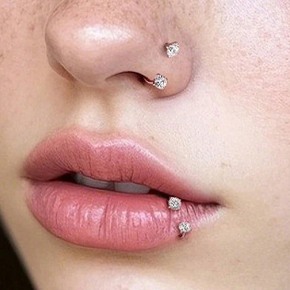 Close-up of a woman's nose and lips adorned with small silver horseshoe stud earrings