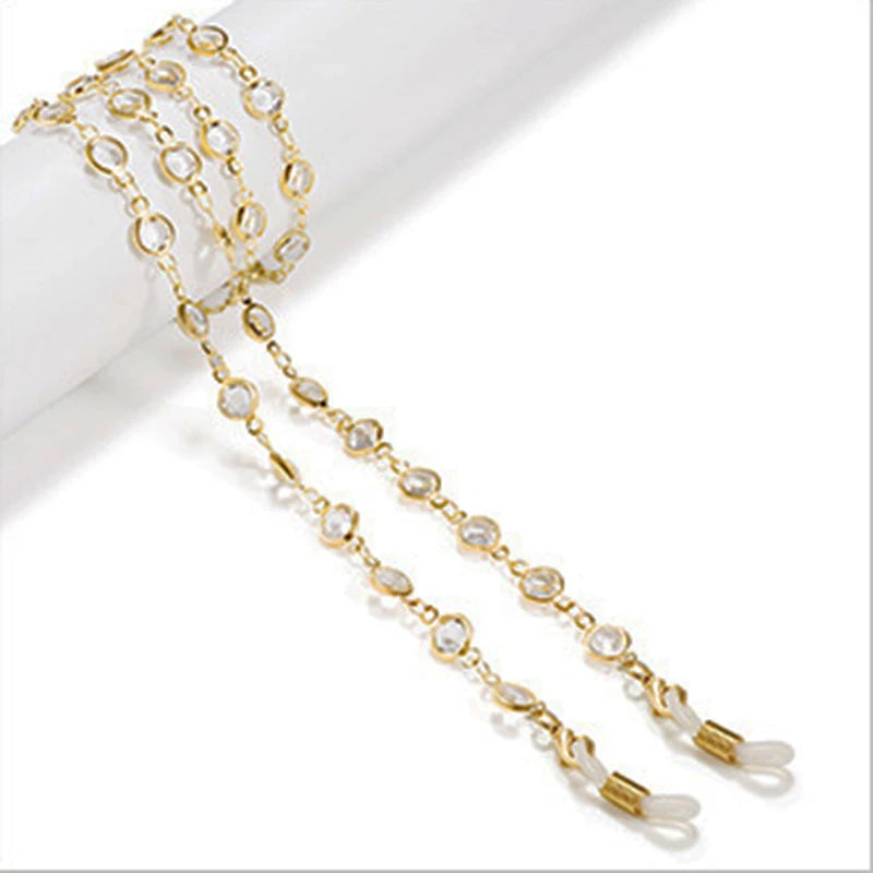 Cadena de cuentas de cristal tono dorado para gafas de mujer, mostrada sobre fondo blanco.