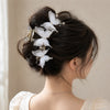 A close-up of a woman's dark hair styled in an elegant updo adorned with pearl rhinestone butterfly hair claw clips.