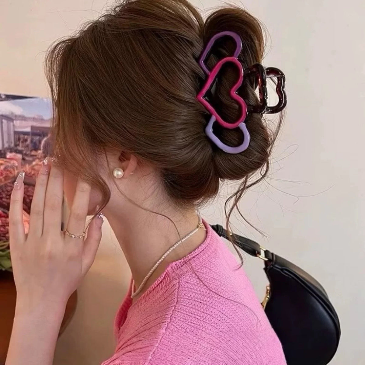 A woman with brown hair styled in an updo shows off heart-shaped hair claws in purple and dark brown.