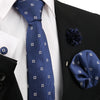 Dunkelblaue gemusterte Krawatte und Accessoires vor schwarzem Sakko und weißem Hemd.
