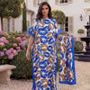 Eine Frau präsentiert ein blau-orange Leopardenmuster-Satin-Abaya-Schal-Set in einem Garten.