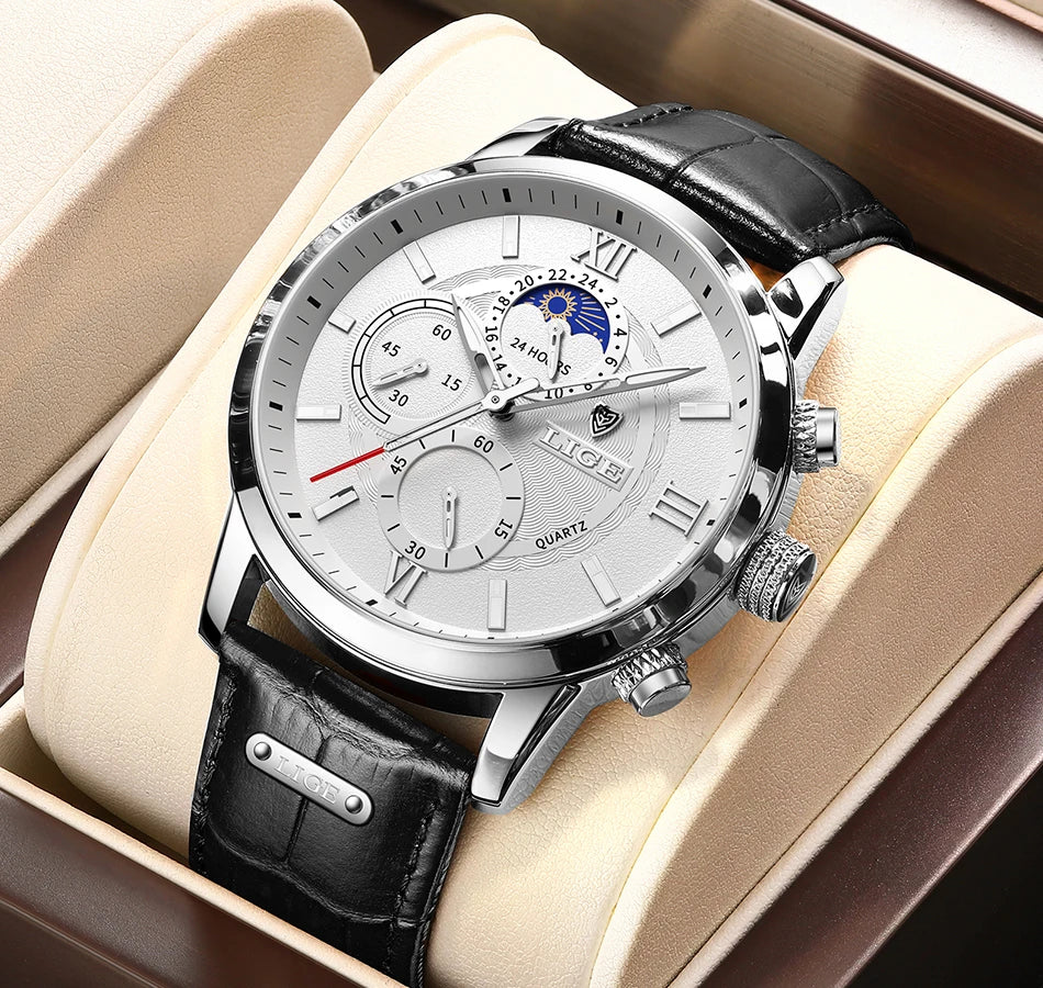 A silver watch with a white dial and black leather strap is displayed in a light brown box.