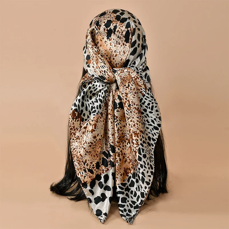 A square satin scarf featuring a leopard print pattern in shades of brown, black, and cream.