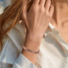 A close-up of a woman's wrist wearing a vintage flower engraved copper bracelet and ring set.