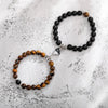 A pair of natural stone heart couple bracelets featuring black and amber beads on silver wire.