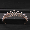 Gold-toned crystal rhinestone bridal tiara headpiece with pearl accents displayed on a black surface.