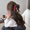 Una mujer con cabello largo y oscuro en cola de caballo alta, adornado con horquillas rosas.