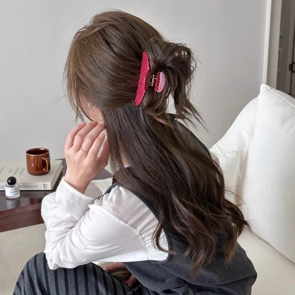 Una mujer con cabello largo y oscuro en cola de caballo alta, adornado con horquillas rosas.