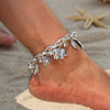 A close-up of a vintage gold elephant charm bracelet worn on a wrist, resting on sandy skin.