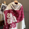 A deep magenta plaid scarf featuring white floral patterns, displayed on a wooden hanger.