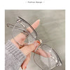 Une main tient une paire de lunettes photochromiques anti-lumière bleue claires.
