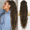 Une femme montre de longues extensions de cheveux bruns ondulés avec un chemisier rayé bleu.