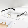 A pair of clear framed glasses with black arms and diamond-edged detailing resting on a white surface.
