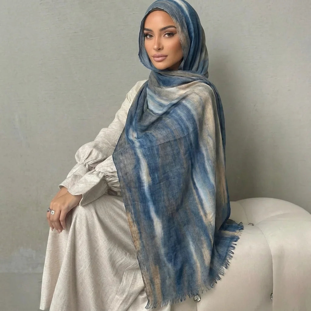 Una mujer vistiendo un elegante pañuelo de hijab a rayas azules y beige con una blusa blanca.