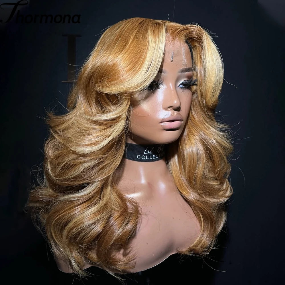 A model wearing a long, wavy honey blonde lace front wig with voluminous layers.