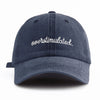A dark navy washed baseball cap embroidered with the word overstimulated
