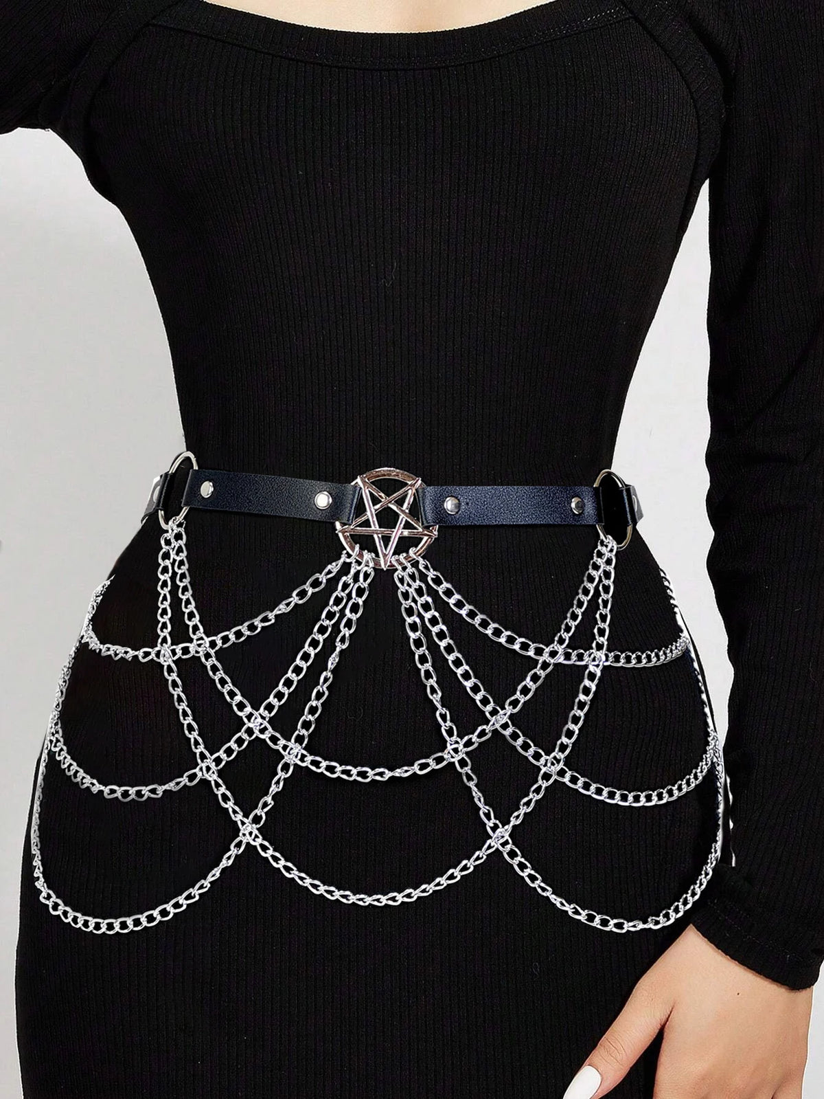 Una blusa negra de manga larga con un cinturón tipo arnés de cadena plateada ajustable.