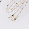 A delicate gold chain lanyard with pearl beads and a charm is displayed against a white background.