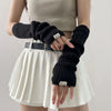 A model wears fingerless arm warmers and a light top with a pleated skirt and a black belt.