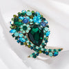 Broche florale en cristal élégante avec des gemmes vertes et bleues.