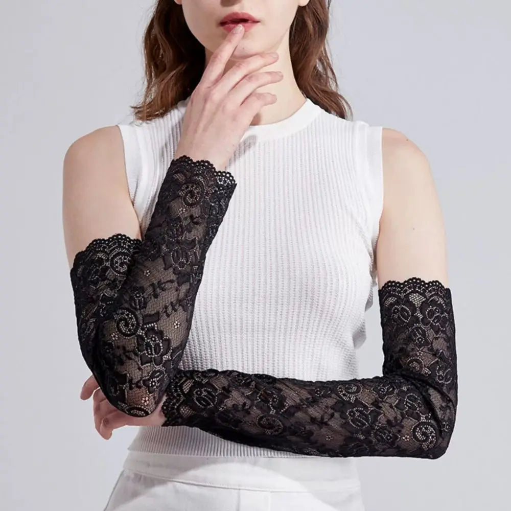 A woman models black lace anti-sunburn arm sleeves on her arm against a light gray background.