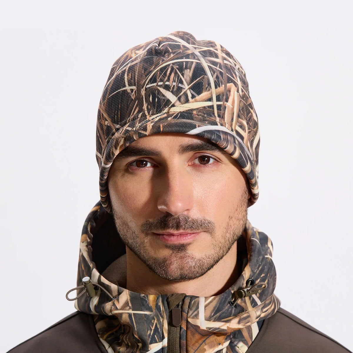 A man wearing a camouflage thermal beanie for outdoor activities.