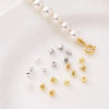 A string of small white pearl beads with a gold-toned connector and various silver jewelry findings spacers.