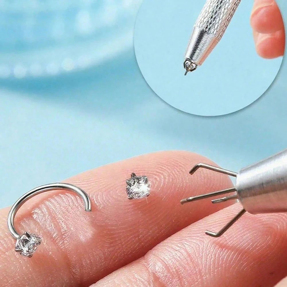 Una mano sostiene un aro de plata y un pendiente de forma de corazón, con un primer plano de una herramienta para perforar.