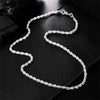 A delicate silver rope charm necklace laid on a black surface.
