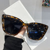 A pair of brown tortoiseshell cat eye sunglasses resting on a white surface.