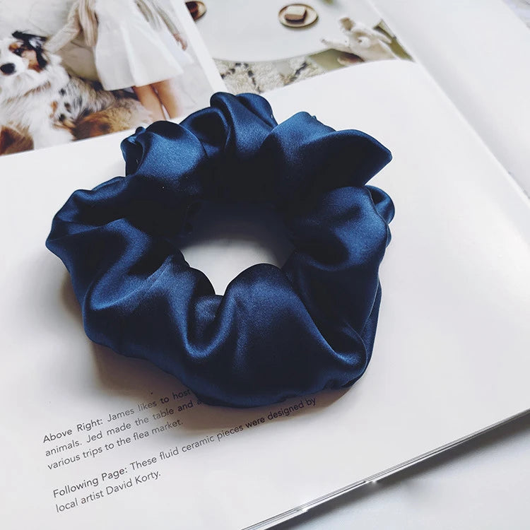 Un lazo para el pelo de seda azul oscuro se muestra en una página blanca junto a texto.