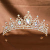 Diadema de tiara barroca de cristal brillante con piedras transparentes e iridiscentes, mostrada sobre tela marrón.